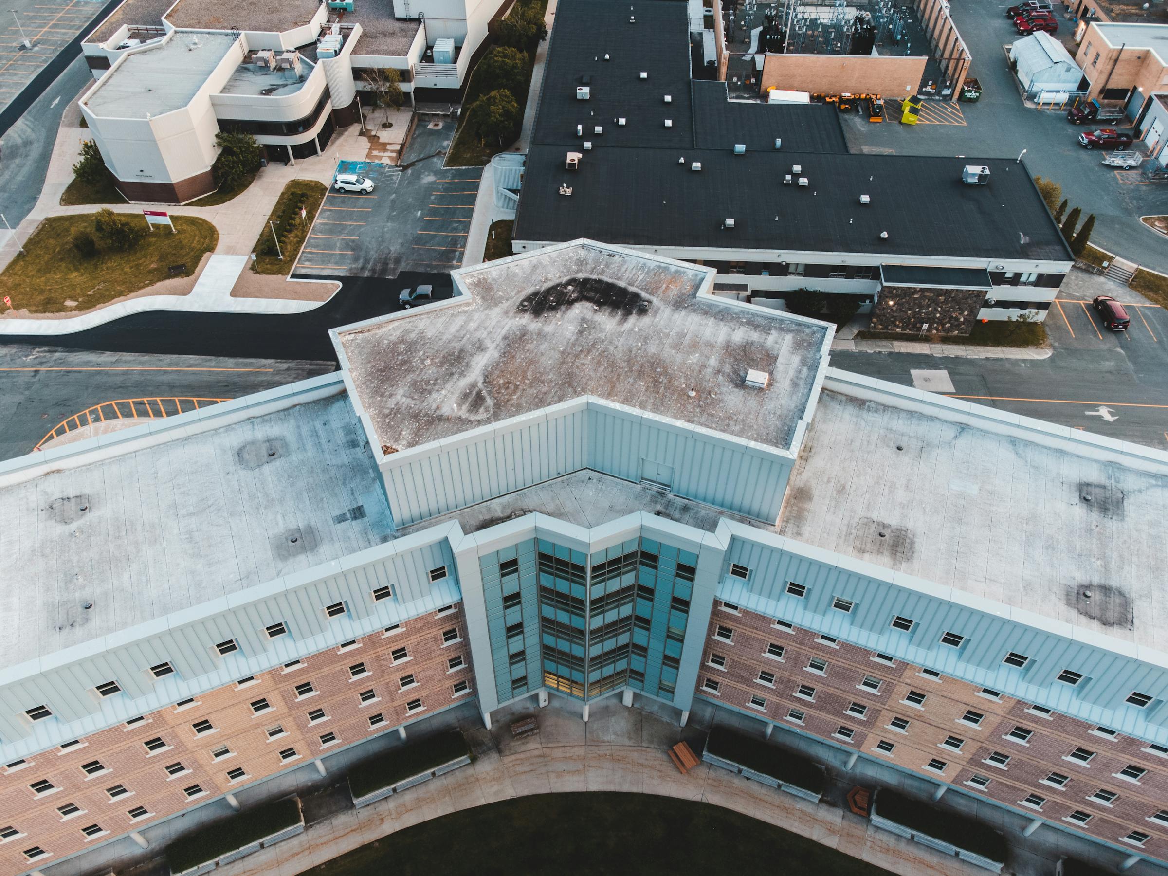 Aerial view of a commercial flat roof showing visible membrane staining and patina — the kind of subsurface damage moisture mapping identifies before it becomes a tear-off